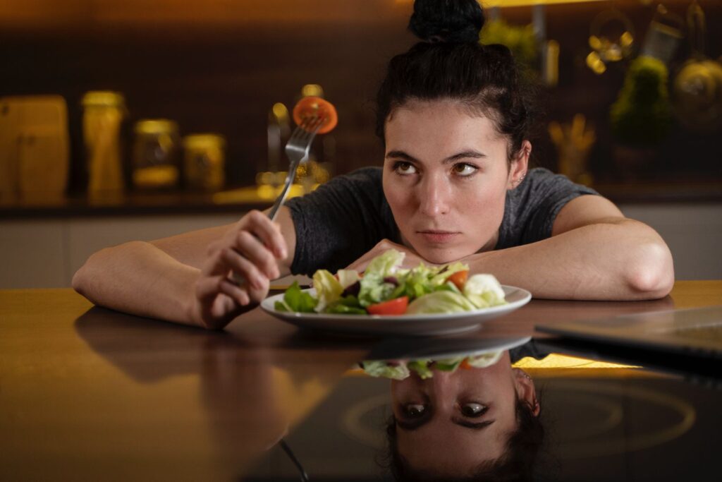 Γυναίκα κάθεται σε ένα τραπέζι μπροστά από ένα πιάτο γεμάτο σαλάτα